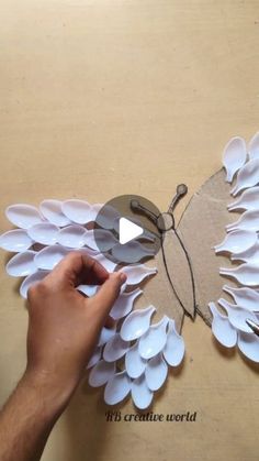 someone is making a butterfly out of paper and glues it on the wall with scissors