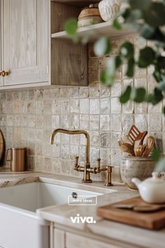 a kitchen with white cabinets and marble counter tops, gold faucets and wooden utensils