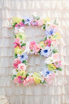 the letter e is made up of flowers and leaves on a white background with ruffled fabric