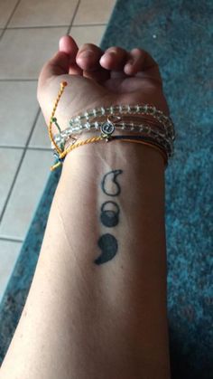 a woman's arm with two bracelets on it and a tattoo design on the wrist