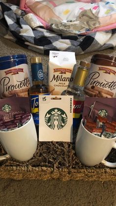 starbucks coffees and other items in a basket on the floor next to a blanket