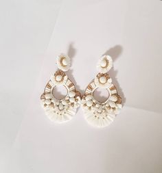 "Boho White and Gold Raffia embellished statement medium size earrings. The earring is hand embroidered using various elements like Raffia, handmade silk pompoms, faux pearl, glass beads, and much more material. This lightweight medium size Raffia white with gold accent earring is a piece of perfect wedding jewelry. The Earrings measure about approx. 2.75\" long and 2.10\" wide. PS: Carnation jewelry is handmade & handcrafted in India hence there is a possibility of a slight or small imperfe Elegant Summer Chandelier Earrings With Tassels, Elegant Summer Tassel Chandelier Earrings, Bohemian White Earrings For Beach, Elegant Summer Chandelier Earrings, Elegant Beige Earrings For Summer, Elegant White Summer Earrings, Chic White Beach Jewelry, White Dangle Tassel Earrings For Party, White Beaded Tassel Earrings For Beach