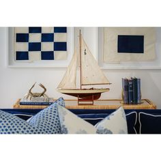 a model sailboat on a table in front of two blue and white wall hangings