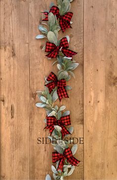 the red and black plaid bow is hanging on a wooden wall with eucalyptus leaves in it