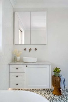 a bathroom with a sink, mirror and bathtub next to a large white tub