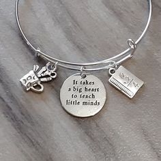 This bangle will make a wonderful gift for that special person in your life or a treat for yourself. Bangle includes: Workbook Charm - approx. 1/4" W x 5/8" L Crafters Cup Charm - approx. 1/2" W x 3/4" L It takes a big heart to teach little minds Charm - approx. 7/8" Round Adjustable Silver-Plated Bangle - high quality silver-plated brass and fits a wrist sized 6"- 8". All charms are made of lead-free, nickel-free antique silver zinc alloy. All orders come in a gift box. Please be sure to read size in the description.      Please message me with any questions. Thank you for looking. Personalized Novelty Charm Bracelet, Adjustable Novelty Charms Bracelets, Inspirational Round Bracelets As Gift, Personalized Inspirational Adjustable Charm Bracelet, Personalized Adjustable Inspirational Charm Bracelet, Inspirational Personalized Adjustable Charm Bracelet, Inspirational Adjustable Personalized Charm Bracelet, Meaningful Adjustable Charm Bracelet, Novelty Bracelet Jewelry For Gifts