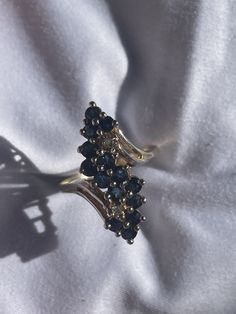 a gold ring with blue stones sitting on top of a white cloth next to a metal object