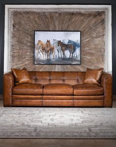 a brown leather couch sitting in front of a painting