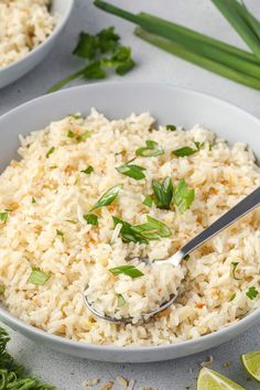 a bowl filled with rice and garnished with parsley next to lime wedges