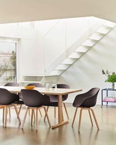 a dining table with six chairs in front of a stair case