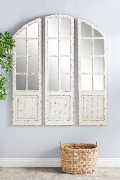 two mirrors are hanging on the wall next to a basket with a plant in it