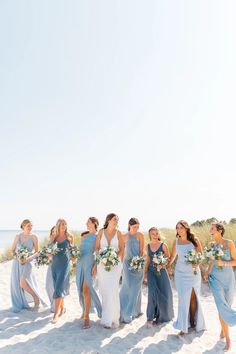 a group of women standing on top of a beach next to each other holding bouquets