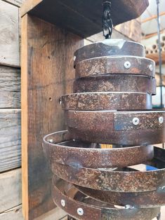 a bunch of metal buckets hanging from a wooden wall next to a wood box