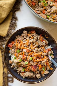 a bowl filled with ground beef and carrots next to another bowl full of rice