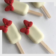 four popsicles with bows on them sitting on top of each other in white and red icing