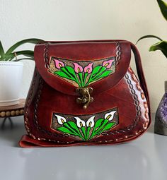 Beautiful, embossed, genuine leather hand tooled floral purse, skillfully made by Artisans in Mexico using the "cincelada" technique. Latch Closure and adjustable strap. Includes a storage bag to protect your purse when not in use.  Dimensions: 11" L x 4" W x 10'' H. Tapered at the top to create a truly unique style. Please check measurements if you have any concerns about sizing before purchase. Includes a dust bag as pictured, to protect your purse when not in use. Imported from Mexico, they a Artisan Hand Painted Brown Bags, Artisan Leather Bags Hand Painted, Traditional Bags With Leather Lining As Gift, Traditional Handmade Leather Satchel, Artisan Embossed Leather Shoulder Bag, Artisan Leather Shoulder Bag With Embossed Detail, Traditional Leather Shoulder Bag With Embossed Detail, Artisan Brown Embossed Shoulder Bag, Traditional Leather Embossed Bags