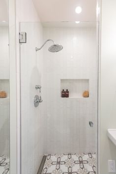 a bathroom with a walk in shower next to a white sink and counter top under a mirror