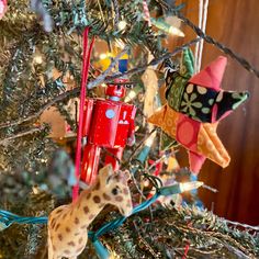 an ornament is hanging on the tree in front of a stuffed giraffe