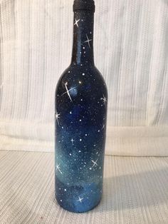 a bottle with stars painted on it is sitting on a white surface and looks like something out of space