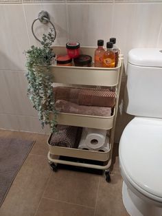 a bathroom with a toilet next to a shelf that has towels and other items on it