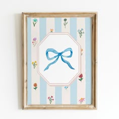 a painting with a blue bow hanging on a white wall next to a striped wall