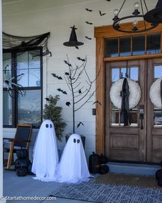 halloween decorations on the front door of a house with two ghost heads and wreaths