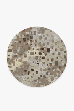 a round area rug with brown and beige squares on the top, in front of a white background