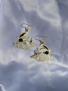 Shimmery black  and white resin in a brass moon shaped setting. Golden hypoallergenic earring hooks are made of 925 silver-plated copper. Each piece is handmade and is created by carefully pouring and mixing resin into each individual section. This tedious process leads to beautiful vibrant colors that imitate a stained glass look in a much more durable and lightweight way. Every piece is naturally unique as it is impossible to maintain the pigment to resin ratio, leading to large variations of Black Metal Moon Shaped Jewelry, Black Metal Moon-shaped Jewelry, White Metal Moon-shaped Jewelry, Handmade Black Enamel Earrings, Handmade Black Moon-shaped Earrings, Unique Moon Phase Metal Earrings, Unique Metal Moon Phase Earrings, Handmade Black Moon Earrings, Black Celestial Earrings For Gift