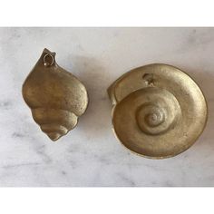 two brass objects sitting on top of a white countertop next to each other,