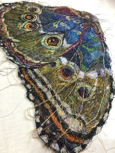 a piece of art that is made out of fabric and yarn with an owl on it