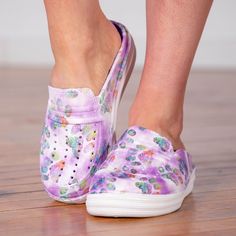 a close up of a person's feet wearing purple shoes with flowers on them