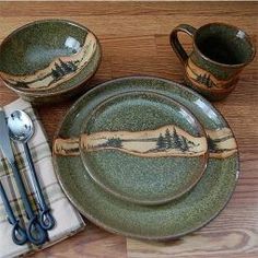 a table set with plates, utensils and spoons on it in the shape of mountains