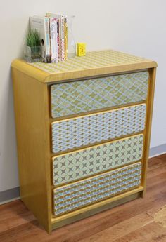 a yellow and blue dresser with some books on it's top shelf next to a white wall