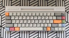 a computer keyboard sitting on top of a white and gray desk with different colored keys