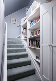 there is a book shelf with books on it and stairs leading up to the second floor