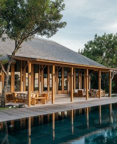 a wooden house sitting on top of a pool next to a lush green forest covered hillside