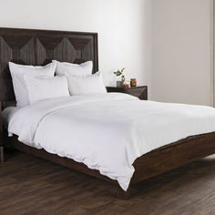 a bed with white sheets and pillows in a room