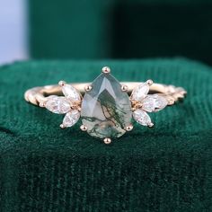 a close up of a ring on top of a green velvet cushion with diamonds around it