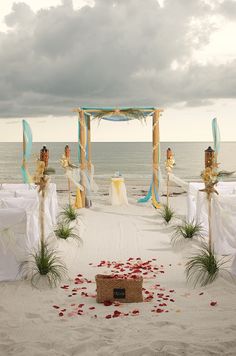 an outdoor wedding setup on the beach with flowers and petals strewn all over the ground