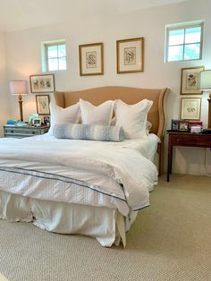 a large bed sitting in a bedroom next to two framed pictures on the wall above it