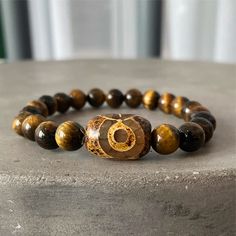 Authentic | High Grade | USA | 3 Days Free Shipping | ASANA Check out our stunning Tiger's eye Tibetan bracelet! Stone: Tiger's Eye - Origin: Tibet - Uses: Luck & Protection Looking for something special to add to your jewelry collection? Check out our gorgeous tiger's eye bracelet! This bracelet is crafted with beautiful tiger's eye beads, each one unique in its colors and patterns. Wear this bracelet as a reminder to stay grounded and connected to your true power. Tiger's eye is known for its Spiritual Brown Gemstone Beads Bracelets, Spiritual Brown Bracelets With Gemstone Beads, Symbolic Natural Stone Beaded Bracelets With Round Beads, Symbolic Natural Stone Beaded Bracelets, Symbolic Beaded Bracelets With Natural Round Beads, Symbolic Beaded Bracelets With Natural Stones, Spiritual Brown Beaded Bracelets With Gemstone Beads, Spiritual Brown Gemstone Beaded Bracelets, Brown Gemstone Beads Bracelets For Meditation