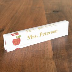 a wooden table topped with a white box filled with an apple and the words mrs petersen