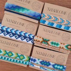 six bracelets with different colors and designs on them sitting on a wooden table next to each other