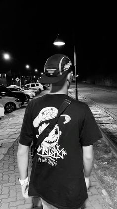 a man is walking down the sidewalk with his back turned to the camera and wearing a baseball cap