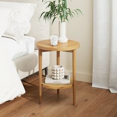 a small wooden table with two white vases sitting on top of it next to a bed