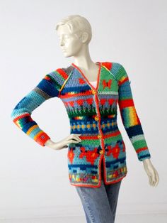 "A 1970s vintage crotchet cardigan. The vibrant rainbow colored hippie sweater features flowers and butterflies in the pattern, a v-neck line, and yellow metal button closures. CONDITION In good condition with wear consistent with age and use. Approximate Size: XS / Small MEASUREMENTS Bust: 30\" Length: 25.5\" Sleeves: 18\" HOW WE MEASURE → Sweater measured lying flat → Bust measured armpit to armpit. → Length measured down the back → Sleeves measured down the underarm from the armpit to end of Fitted Bohemian V-neck Sweater, Multicolor Retro Cardigan With Buttons, Retro Multicolor Buttoned Cardigan, Retro Multicolor Cardigan With Buttons, Fitted Multicolor Retro Cardigan, Vintage Multicolor Cardigan For Festivals, Vintage Multicolor Cardigan With Buttons, Vintage Multicolor Festival Cardigan, Bohemian Multicolor V-neck Sweater