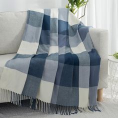 a blue and white plaid blanket sitting on top of a couch next to a potted plant