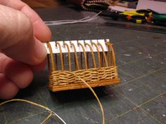 a person is holding a miniature piece of wood and string in front of a small object