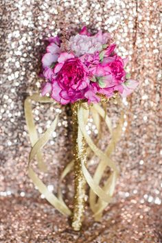 a bouquet of pink flowers sitting on top of a gold vase filled with purple flowers