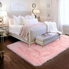 a white bedroom with pink rugs on the floor